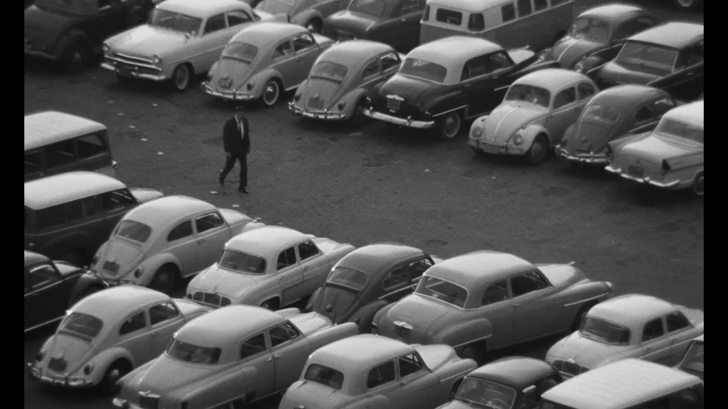 Homem caminha entre carros em cena de São Paulo Sociedade Anônima, retratando a alienação do trabalho e da vida urbana