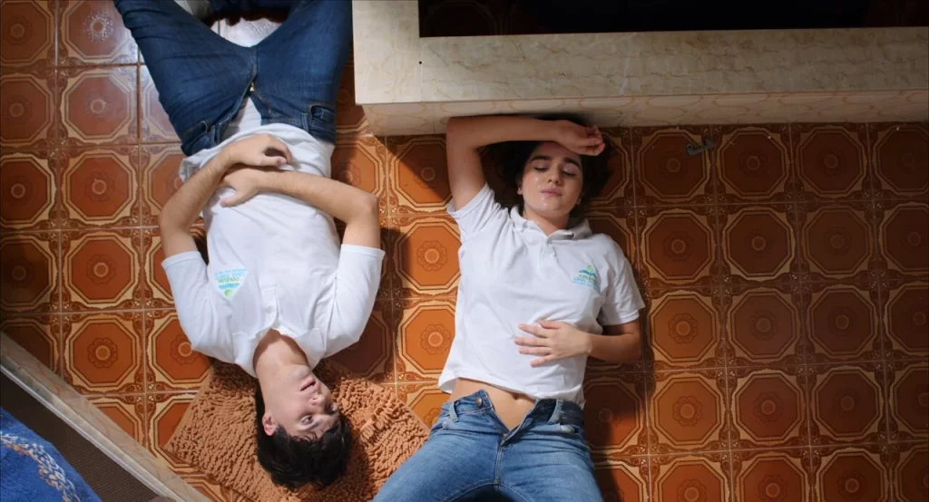 A Miss – irmãos lidam com expectativas familiares Cena do filme brasileiro A Miss mostra irmãos gêmeos deitados no chão enquanto lidam com conflitos familiares.