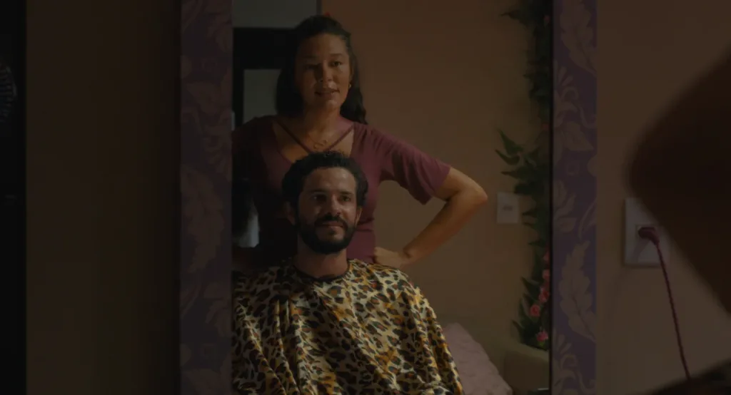 Vicente conversa com uma mulher enquanto corta o cabelo em uma cena de Leite em Pó.